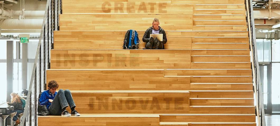photo of two students sitting on stairs of Norm Asbjornson Hall