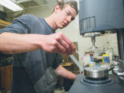 Student working in Magnetic Resonance Lab, placing sample under scanner